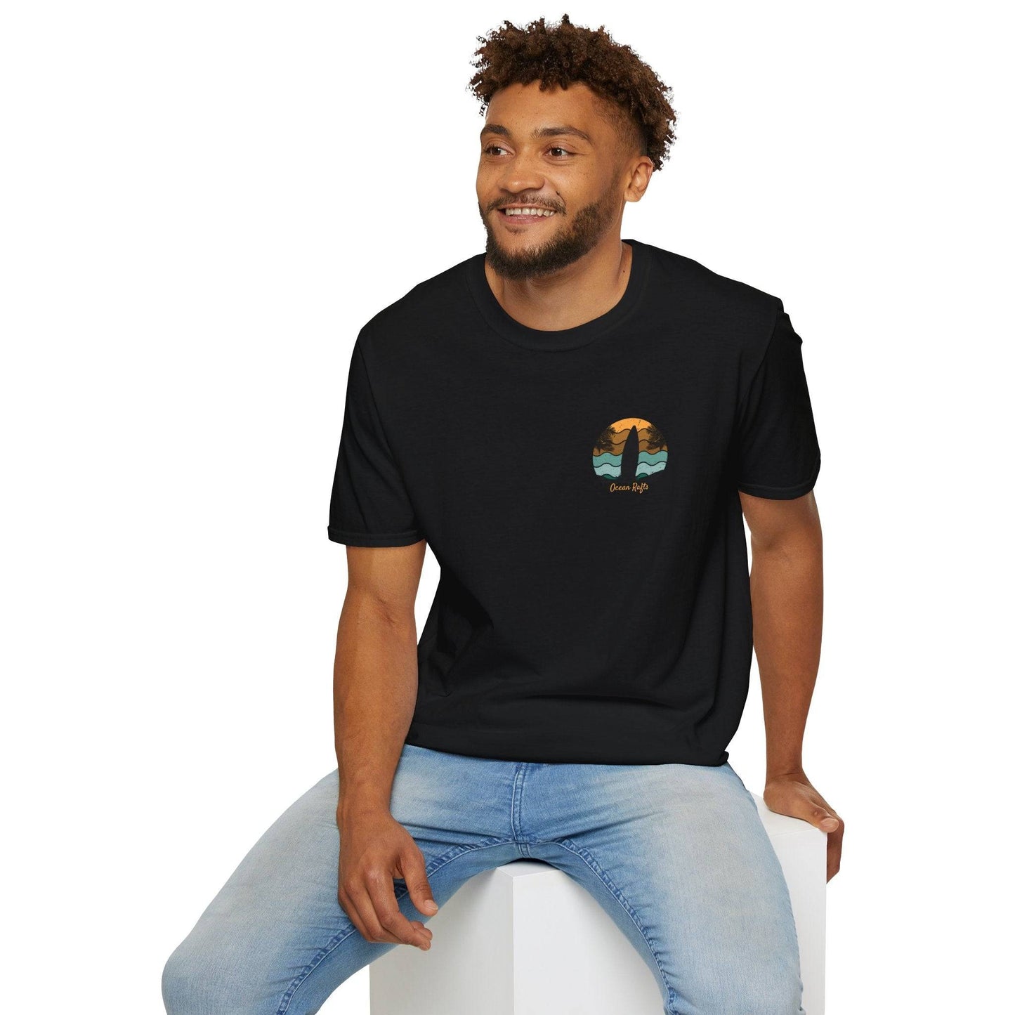 man wearing black shirt sitting down and looking in distance regular fit leightweight shirt for men and women with surfboard palm trees and beach graphics back and front with surfing and camping and ocean rafts text $40 free delivery cheap | Ocean Rafts