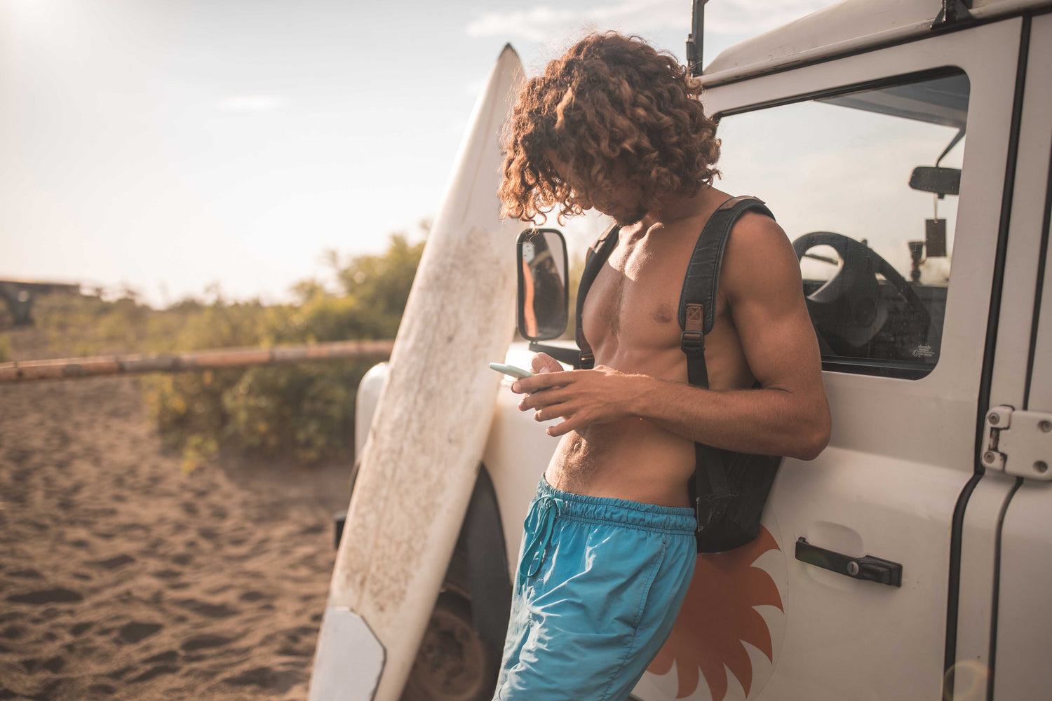 man leaning on van with surfboard looking at his phone www.oceanrafts.com ocean rafts home page contact us section