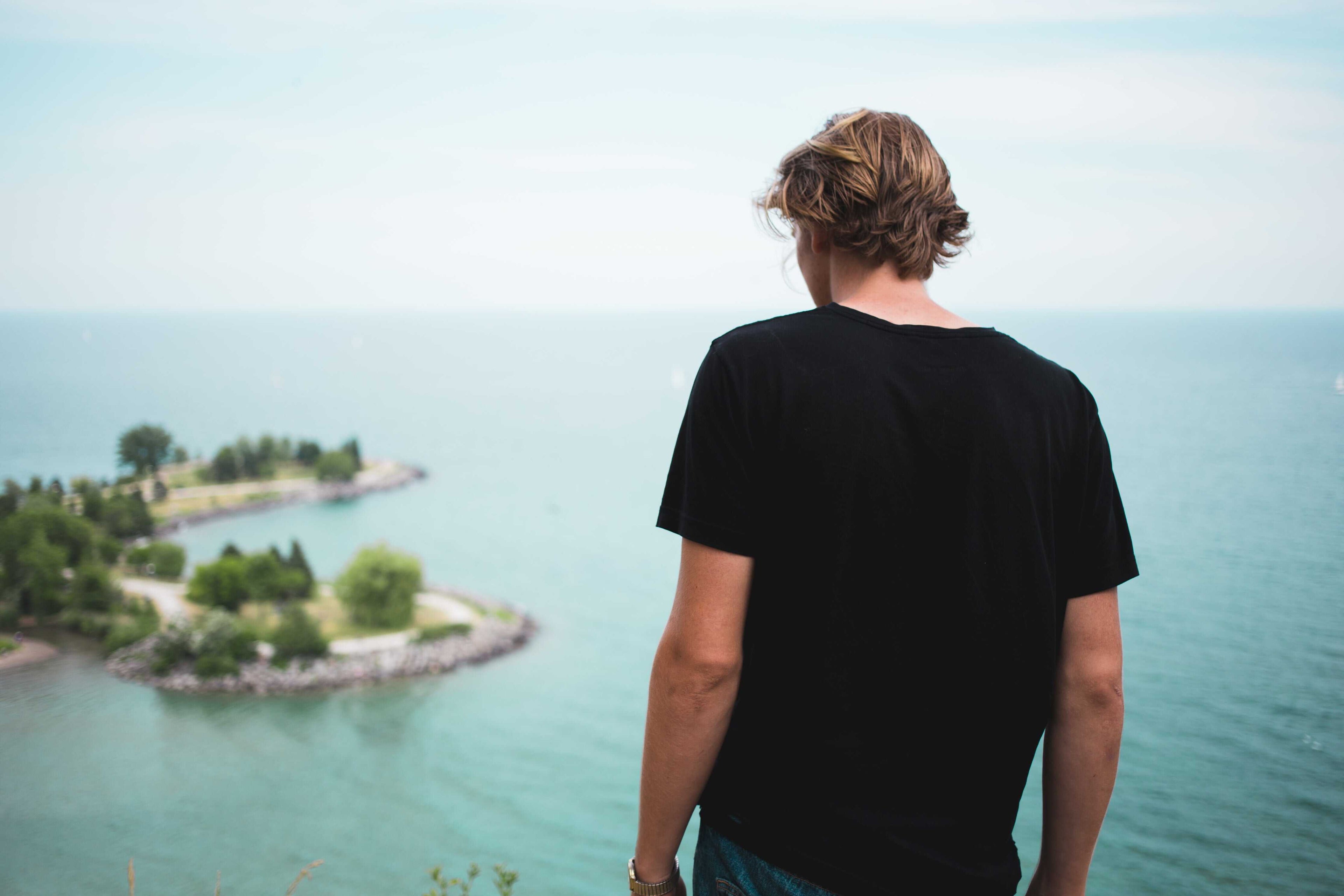 man wearing t shirt over looking island and sea www.oceanrafts.com home page over sized t shirt and regular fit t shirt section