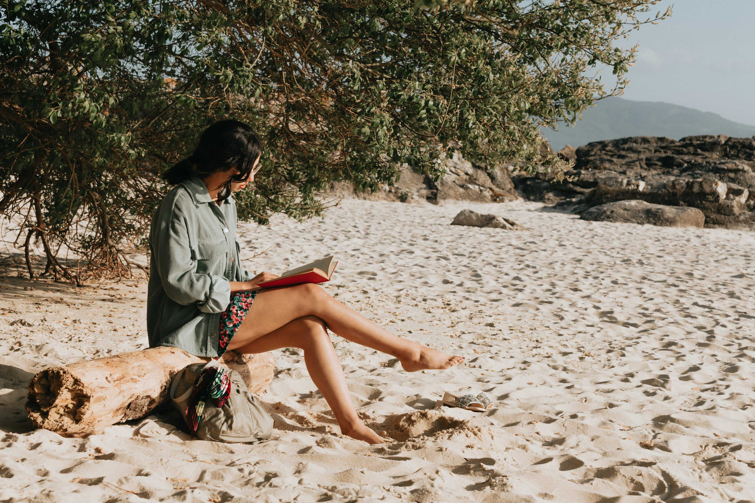 lady reading book while sitting on log on the beach www.oceanrafts.com ocean rafts home page our story section